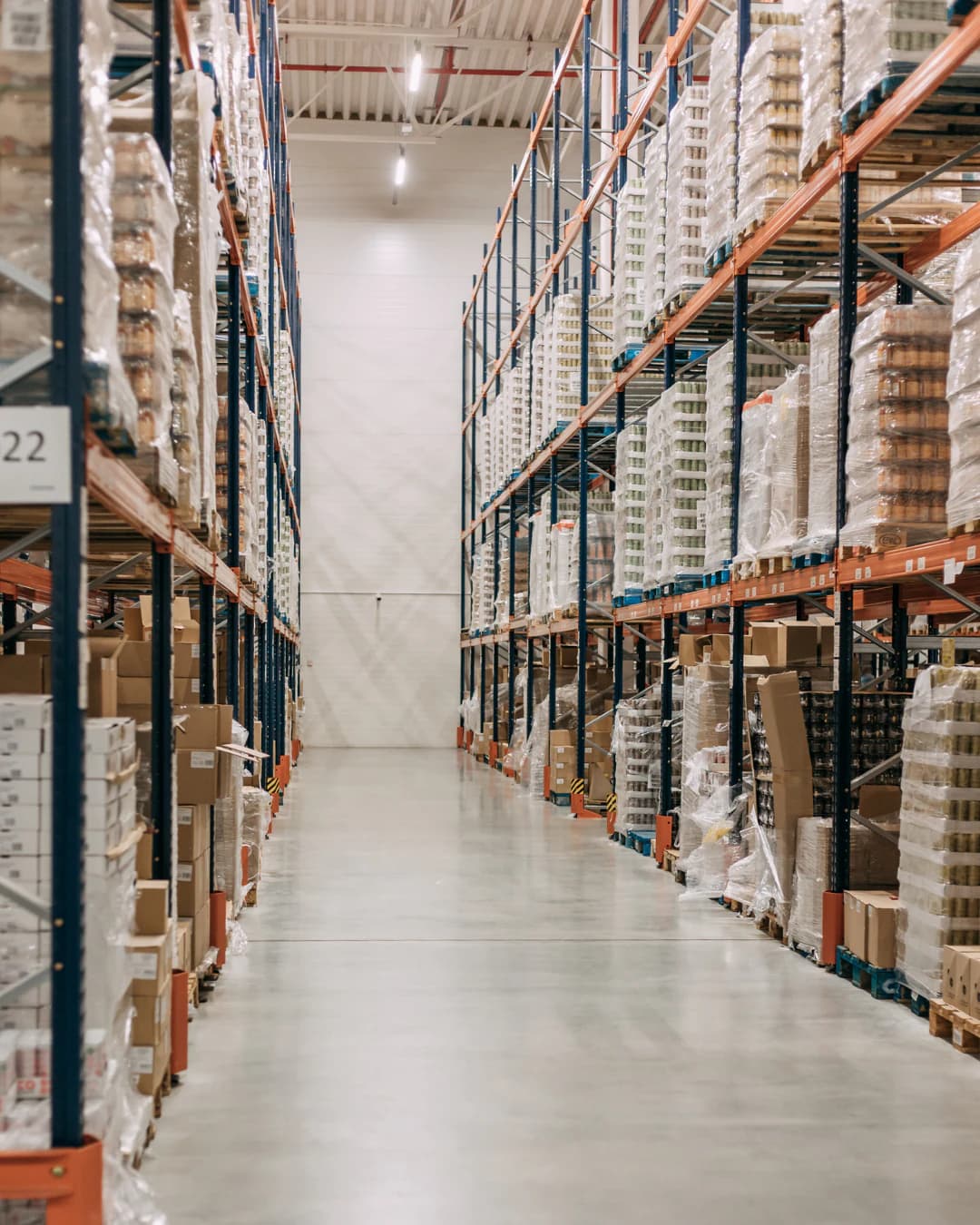 An aisle of high-bay racking filled with pallets of goods