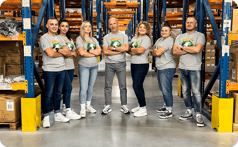 The Completio team posing together in the warehouse hall between racking