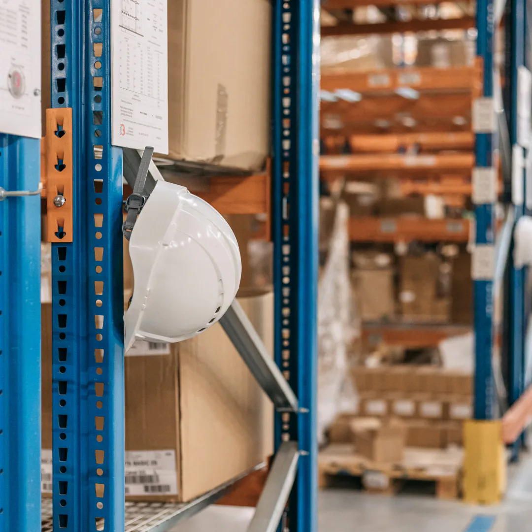 A white safety helmet hanging on a pallet racking upright